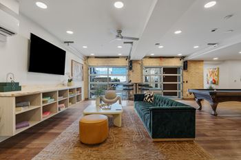 A living room with a green couch and a television on the wall.